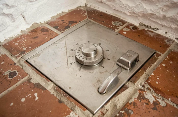 Gros plan sur le cadran d'un coffre-fort scellé dans le sol en carrelage terre cuite d'une villa méditerranéenne