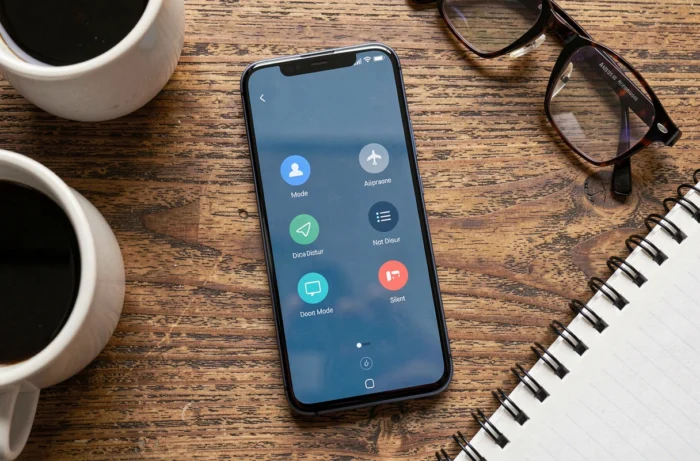 Vue de dessus d'un smartphone Android affichant les options de mode avion, ne pas déranger et mode silencieux sur une table en bois